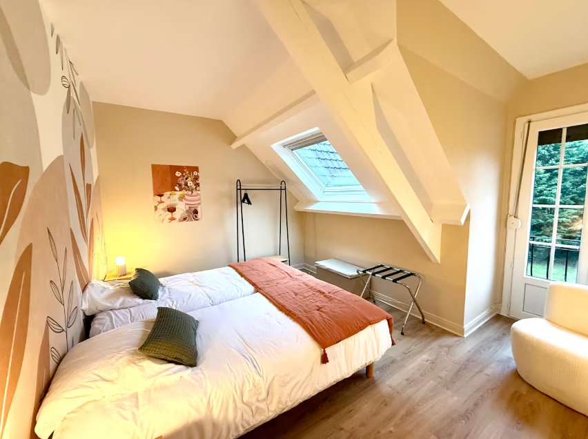 Chambre sous les toits, au mur décoré de feuillages, avec un lit king size et un velux