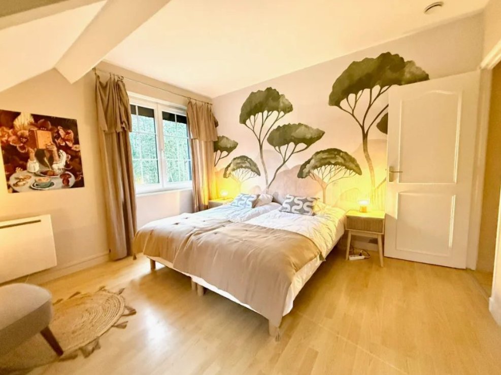 Chambre aux tons doux, avec un mur peint d'arbres et un grand lit