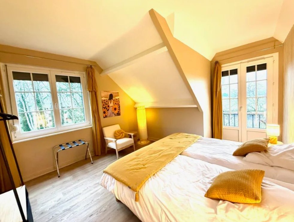 Chambre lumineuse aux tons dorés, avec fenêtres sur les arbres