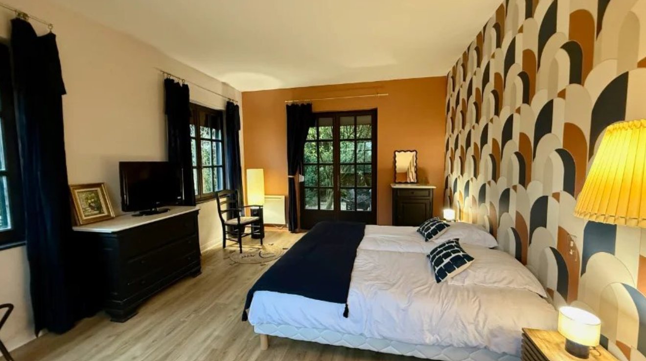 Chambre au papier peint à motifs d'arches, avec porte-fenêtre sur le jardin