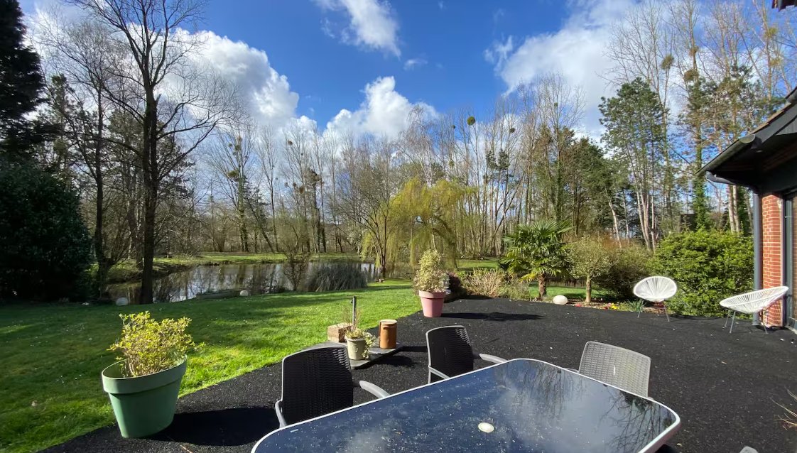 La terrasse face au jardin et à l'étang, sous un grand ciel